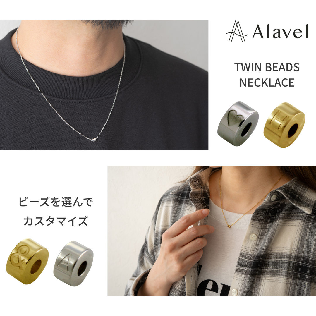 Alavelツインビーズネックレスの広告、男性がシルバーのネックレスを着用し、女性がゴールドのネックレスを着用