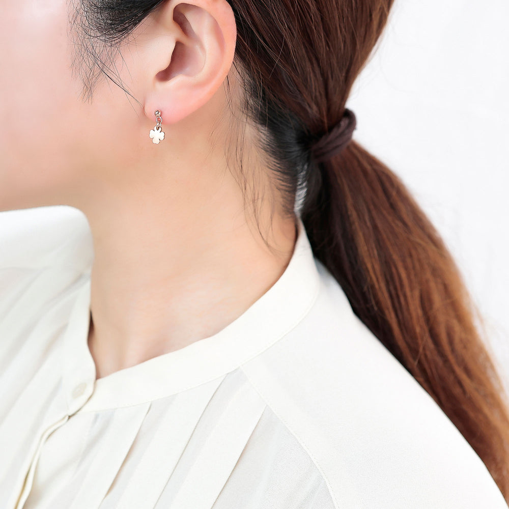 女性の耳にクローバーのチャームが付いたイヤリング
